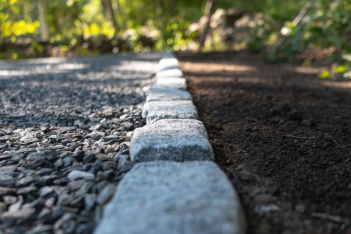 Cobblestone border separating crushed bluestone and fresh loam.