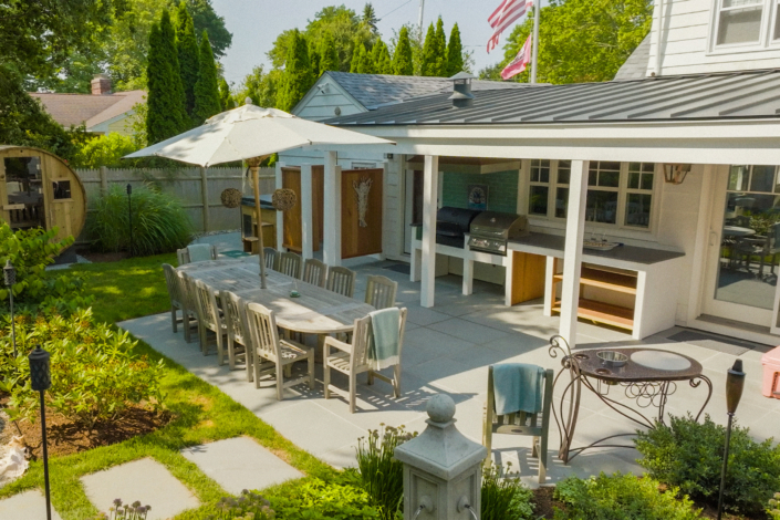 Stepping stones leading to a backyard bluestone patio with a picnic table, a bar, and an outdoor shower.