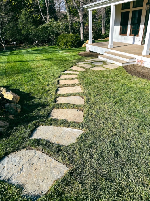 Irregular bluestone arranged in a curved stepping stone walkway leading to an accessory dwelling unit.
