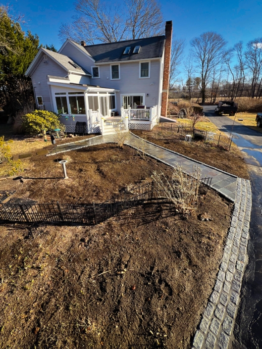 A cobblestone apron leading to a natural cleft bluestone walkway on the back side of a home.
