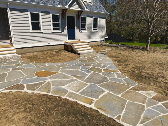 Irregular flagstone patio connecting multiple entrances to the side of a house.