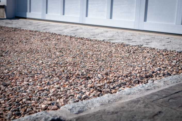 Detailed view of a crushed stone driveway with a cobblestone apron and border.