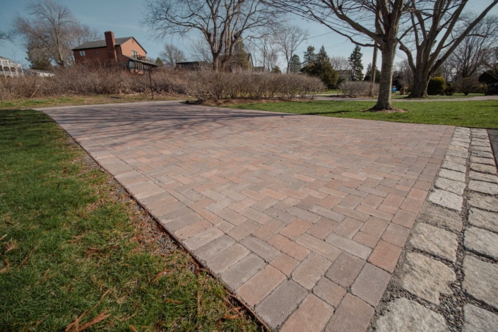 Herringbone pattern driveway with cobblestone aprons using Copthorne pavers from Unilock in Jamestown, Rhode Island.