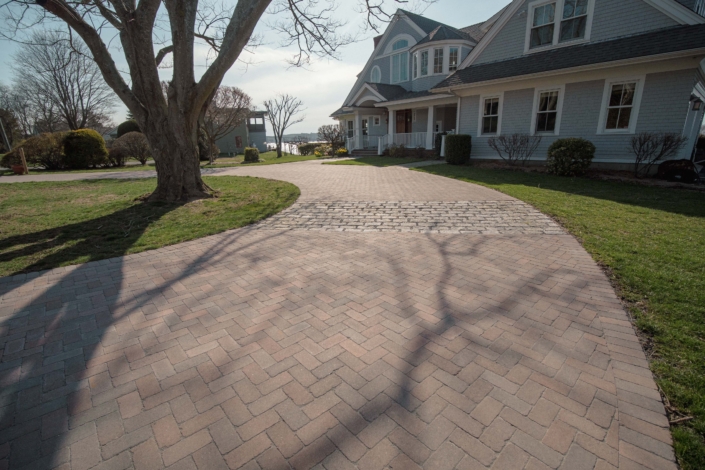 Herringbone pattern driveway with cobblestone aprons using Copthorne pavers from Unilock in Jamestown, Rhode Island.